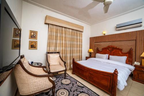 白沙瓦Shelton House Peshawar的一间卧室配有一张大床和一把椅子