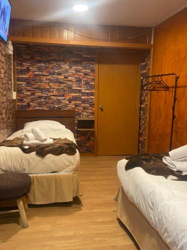 安库德Hostal Queltehue的一间卧室设有两张床和砖墙