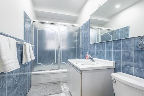多伦多Littlewood Properties的蓝色瓷砖浴室设有水槽和淋浴