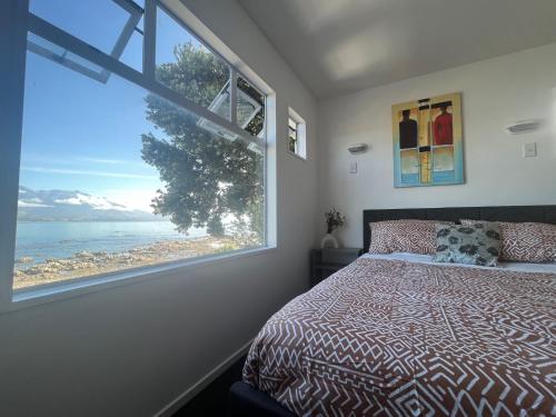 凯库拉Kaikoura Seaside lodge的一间卧室设有一张床和一个大窗户