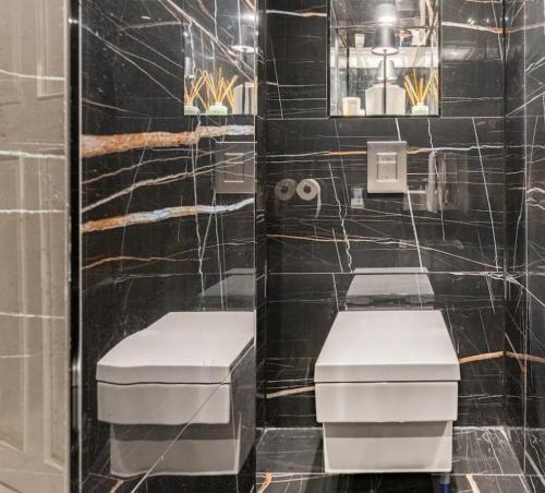 爱丁堡Luxury New Town Apartment的黑色瓷砖浴室设有2个卫生间和镜子