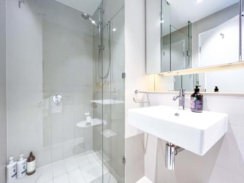 墨尔本精采维多利亚港海滨公寓的白色的浴室设有水槽和淋浴。