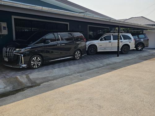 七岩Pool Villa Baan Sanook Cha-am的两辆汽车停在大楼旁边的停车场
