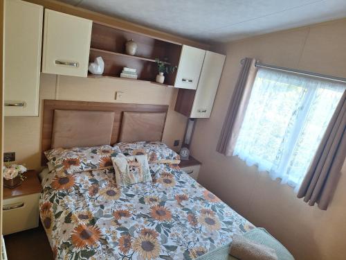 阿贝尔格莱Countryside Caravan Accommodation - Abergele的一间卧室配有一张带花卉棉被的床和窗户。