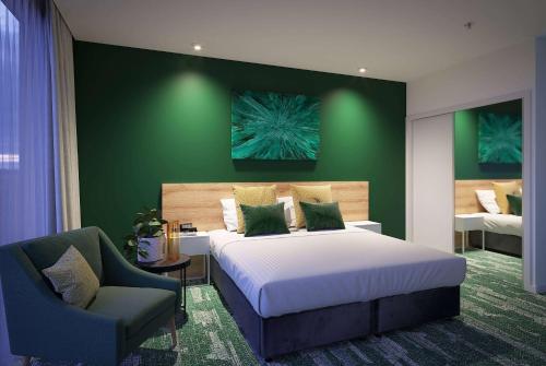 奥克兰La Quinta by Wyndham Ellerslie Auckland的一间卧室配有一张大床和一把椅子