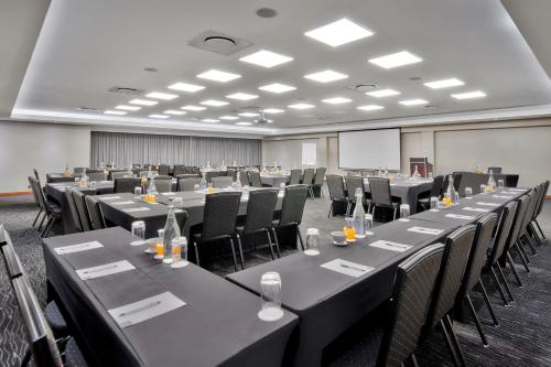 比勒陀利亚Protea Hotel by Marriott Pretoria Hatfield的一间会议室,配有桌椅和屏幕