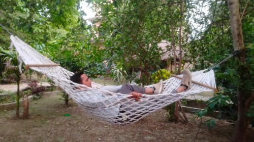 索拉哈Hotel Tiger Tops Sauraha的躺在花园吊床上的男人