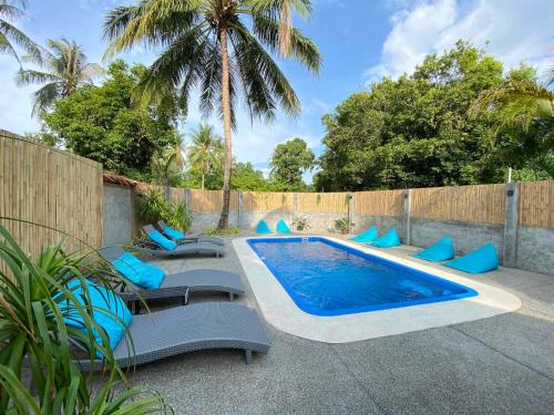 高兰慵懒时光简易别墅旅馆的一个带蓝色软垫椅子的游泳池,靠近围栏