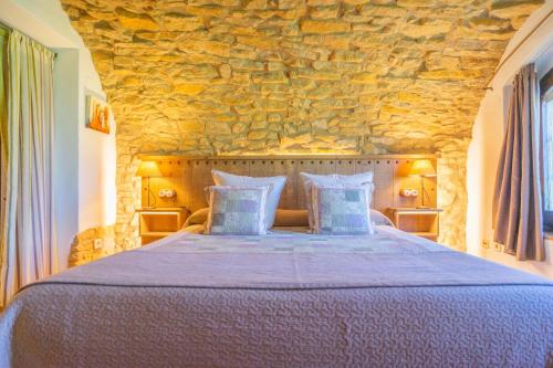佩拉托拉达Hotel Mas Rabiol -Costa Brava-Emporda-Only Adults的一间卧室设有一张带石墙的大床