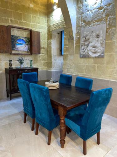 KerċemDaner Ta’ Pantu House的一间带木桌和蓝色椅子的用餐室