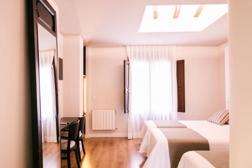 卡拉瓦卡·德·拉·克鲁斯Hotel La Vera Cruz的一间卧室设有两张床、一张桌子和一个窗口。