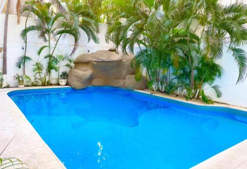 阿卡普尔科Acapulco Hotel y suites mediterrane的一座棕榈树游泳池,位于酒店大楼旁