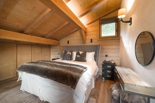 梅杰夫Luxury Megève Chalet, sleeps 8 with Mountain Views and Jacuzzi的一间卧室设有一张床和木制天花板