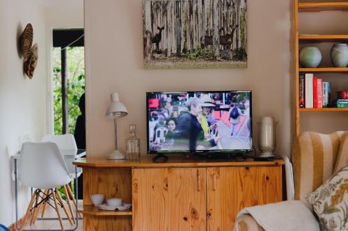 姆巴巴内Vista Garden Cottage的一间客厅,客厅内配有一台电视,位于一个木制娱乐中心