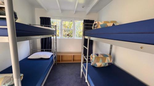 欧尼罗亚Hekerua Lodge Backpackers Hostel Waiheke Island的客房设有两张双层床和一扇窗户。