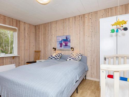 NibeHoliday home Nibe VI的卧室配有一张床铺,位于带木墙的房间内