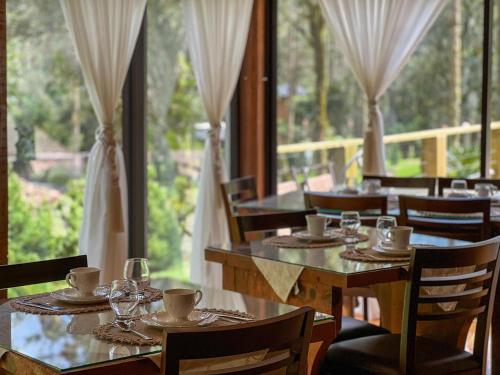 乌鲁比西Pousada Encanto do Avencal的餐厅设有桌椅和大窗户。