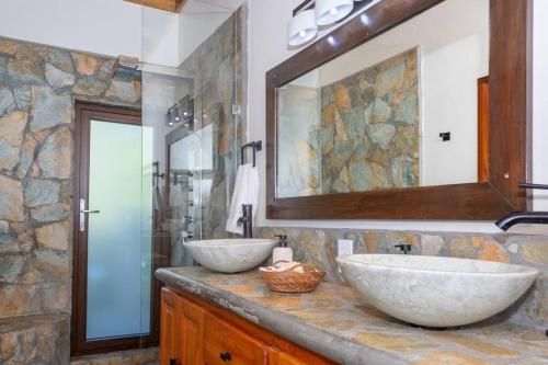 罗阿坦Apricari House Stunning Views 3 BDRM and Pool的浴室设有石墙和2个水槽。