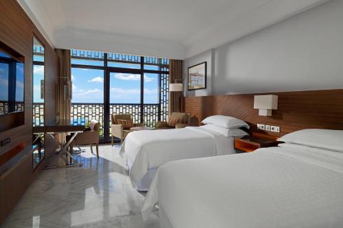 突尼斯突尼斯喜来登酒店的酒店客房带两张床和一张桌子以及椅子。