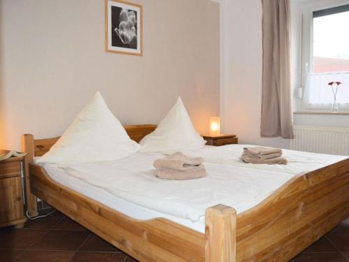 诺德代希Windrose Comfortable holiday residence的一间卧室配有一张带白色床单的木床和窗户。
