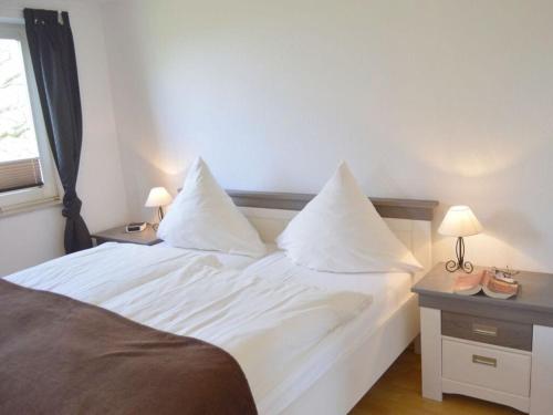 诺德代希Deichstübchen Comfortable holiday residence的一间卧室配有带白色床单和枕头的床。
