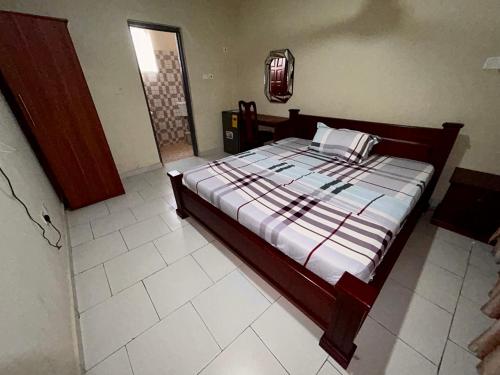 ApenkwaJessie Hotel的卧室配有一张铺有白色瓷砖地板的床。
