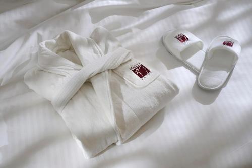 尼科西亚塞莫利酒店 的床上的白色毛巾和一双鞋