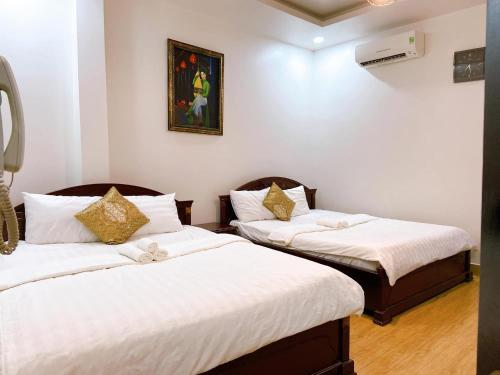 Cái RăngKhách Sạn Hoàng Lộc Phát的配有白色床单的客房内的两张床