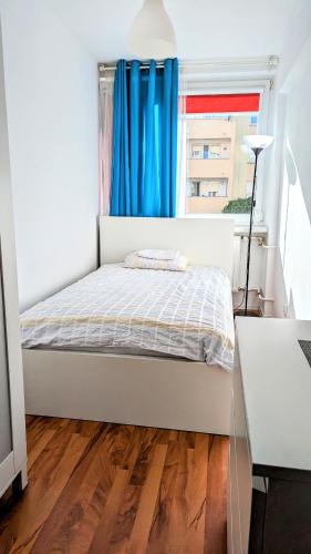 华沙Ursus Rooms-Self Check-in的一间卧室配有床和蓝色窗帘的窗户