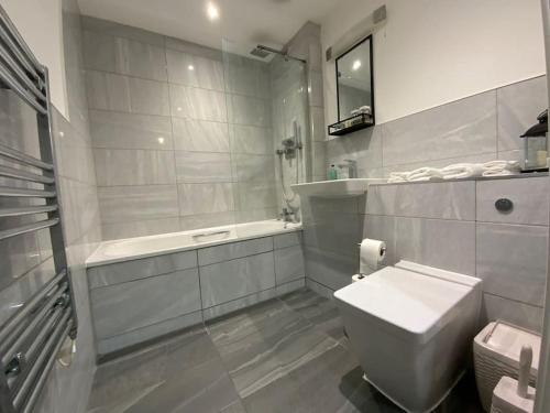 布伦特伍德Modern 1 bedroom serviced apartment with garden的浴室配有卫生间、盥洗盆和浴缸。