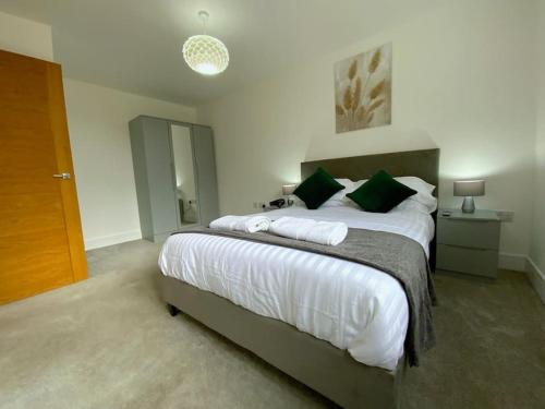 布伦特伍德Modern 1 bedroom serviced apartment with garden的一间卧室配有一张带绿色枕头的大床