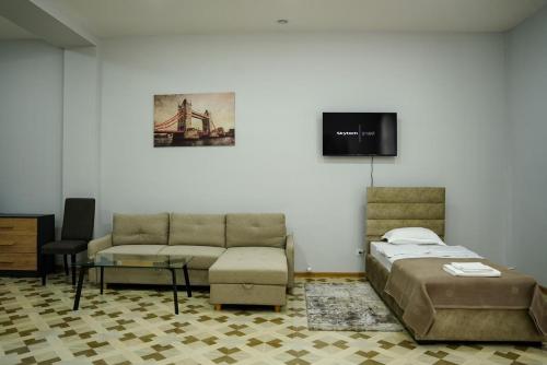 久姆里Square Inn的一间卧室配有一张床、一张沙发和一台电视。