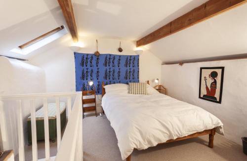 威弗利斯科姆Garden Cottage, Wiveliscombe的卧室配有白色的床和蓝色的窗户。