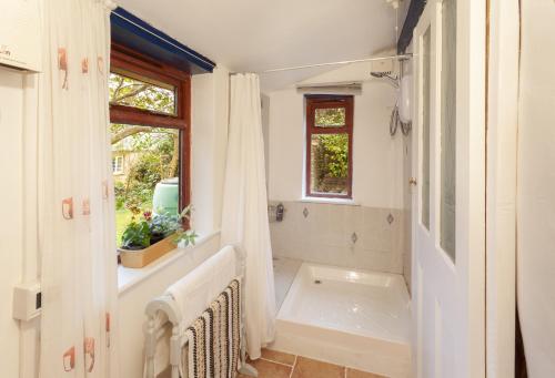 威弗利斯科姆Garden Cottage, Wiveliscombe的白色的浴室设有浴缸和窗户。