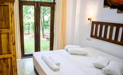 波隆纳鲁沃Ceylan Rock Luxury Apartments的一间卧室配有一张带白色床单的床和一扇窗户。