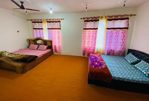 斯利那加Adeel Homes Srinagar的配有粉红色窗帘的客房内的两张床
