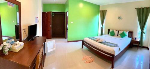 高兰Lanta Just Come Hotel的一间卧室设有绿色的墙壁、一张床和一张书桌