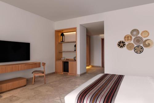 塞拉莱The Club by Fanar的配有一张床和一台平面电视的酒店客房