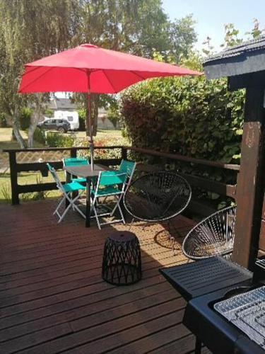 普勒尔蒂Mobil home centre ville的庭院配有桌椅和红色遮阳伞。