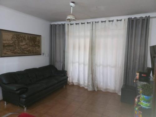 里贝朗普雷托SOBRADO Zona Sul Ribeirao Preto的客厅配有黑色沙发和白色窗帘