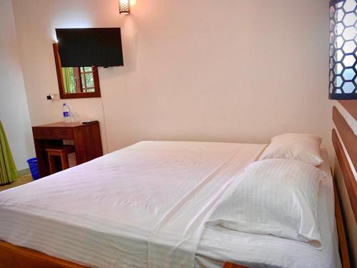 库鲁内格勒Raddagoda walawwa Hottel的卧室内的一张带白色床单和枕头的床