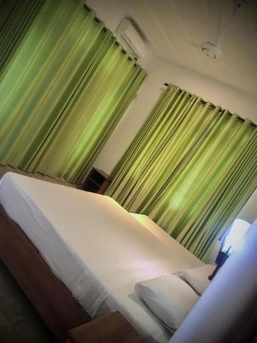 库鲁内格勒Raddagoda walawwa Hottel的一间卧室配有一张带绿色窗帘的大床