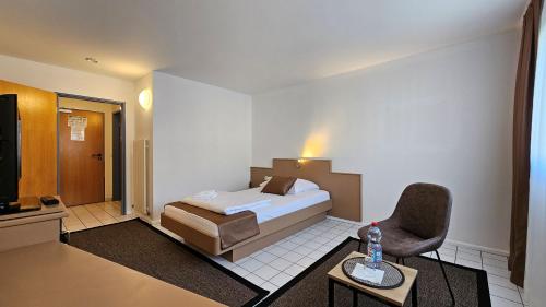 斯图加特Elha Hotel的配有一张床和一把椅子的酒店客房