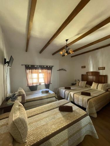 La Puerta de SeguraLa magnolia的一间卧室设有三张床和天花板
