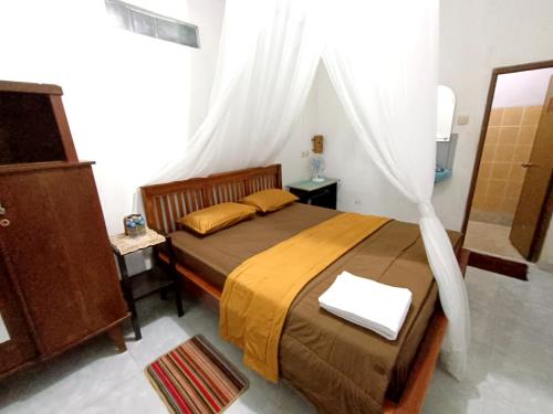 姆杜克Jojo's Warung & Homestay的一间卧室配有一张带天蓬的床