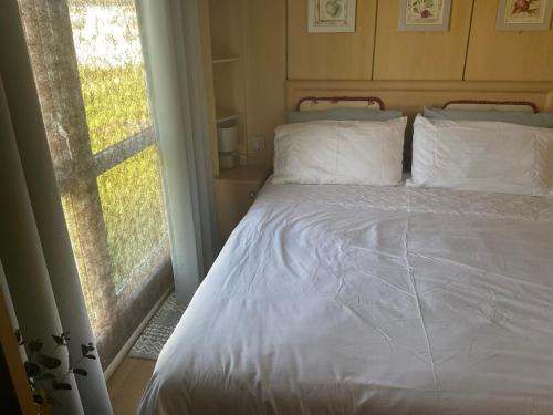GreatstoneRomney Sands holiday home的一张带白色床单和枕头的床,靠窗