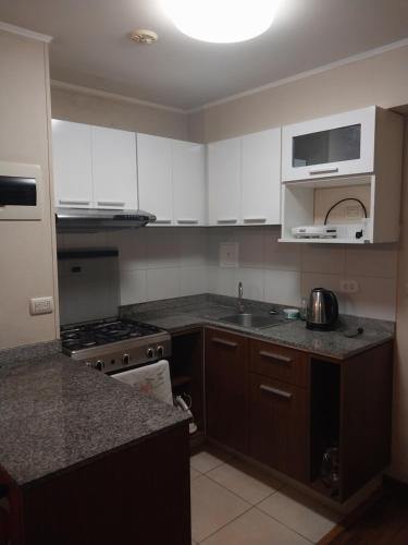利马departamento de 1 dormitorio的厨房配有白色橱柜、水槽和炉灶。