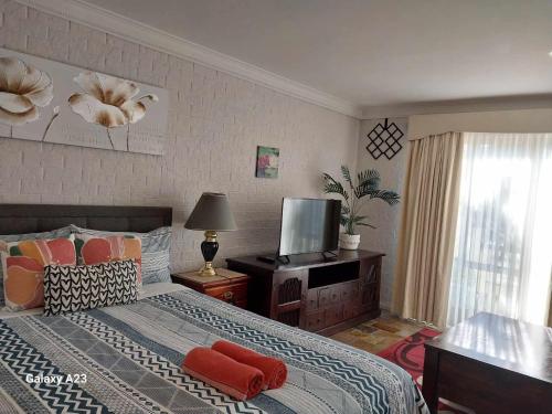 堪培拉Sweet Home by the Golf Course的一间卧室配有一张带红色枕头的床和电视。
