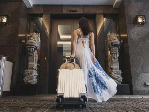 那霸Okinawa EXES Naha的穿着白色衣服的女人拉着行李箱