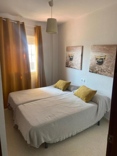 桑卢卡尔-德巴拉梅达Atico en Sanlucar的一间卧室配有一张带两个黄色枕头的床